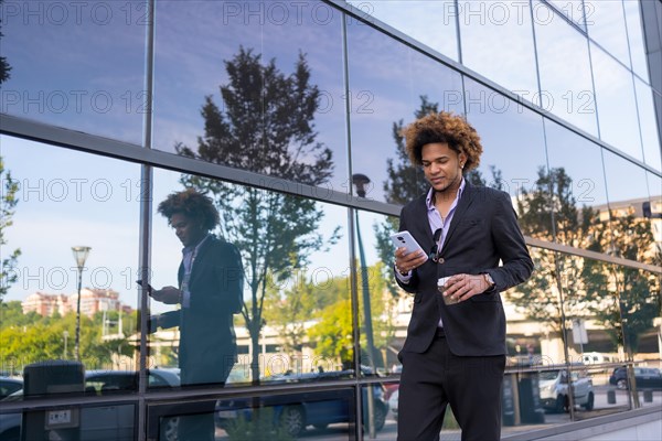 Horizontal portrait with copy space of a brunette businessman walking using phone and drinking coffee