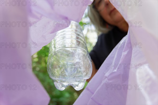 Woman puts a plastic bottle in a garbage bag as seen from inside the bag