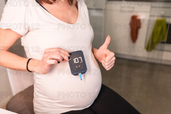 Young pregnant woman performing a gestational diabetes self-test to control sugar. Positive blood test result