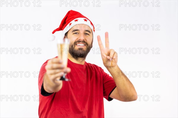 Young very happy Caucasian man with red Christmas hat toasting with a glass of champagne on a white background