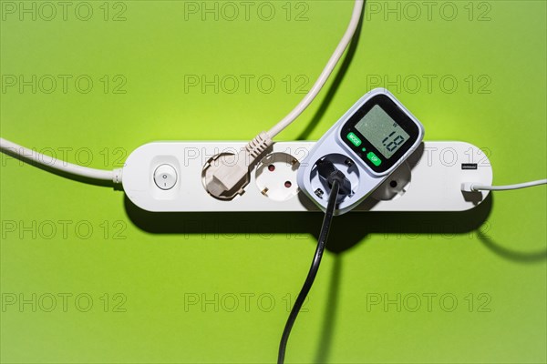 Top view of an energy cost meter in a power strip against a green background