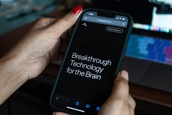 In this photo illustration a person browses Neuralink website on a smartphone