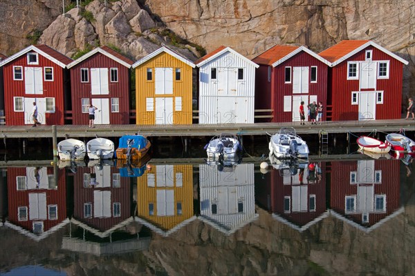 Colourful traditional fishing huts and boathouses along wooden pier at Smoegen