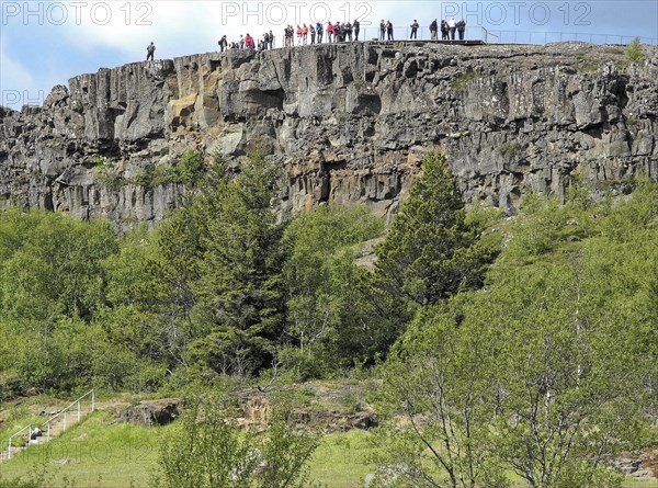 Tourists on a rock in Thingvellir National Park in the southwest of Iceland. The national park is a UNESCO World Heritage Site. Capital Region
