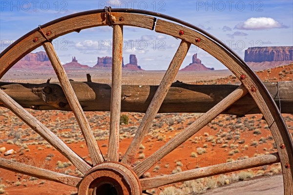 Buttes of Monument Valley seen through old wooden wagon wheel