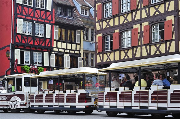 Colorful facades of timber framed houses and sightseeing train with tourists at Colmar