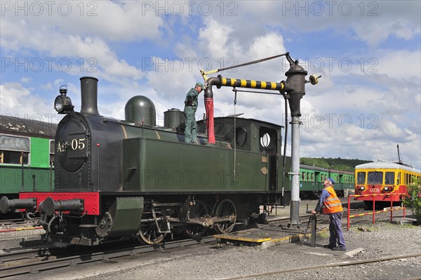 Engine driver filling boiler of steam train from water crane at the depot of the Chemin de Fer a Vapeur des Trois Vallees at Mariembourg