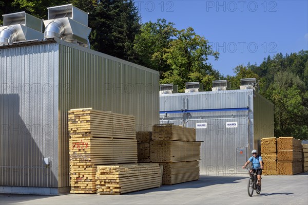 Stacks of wooden beams and boards in front of a timber drying plant in a sawmill