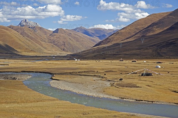 Tibetan nomadic tents with prayer flags and herd of yaks grazing along the Sichuan-Tibet Highway