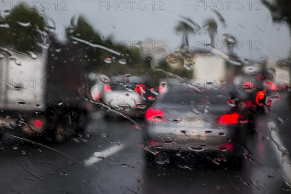 Trucks overtaking cars on highway during heavy rain shower seen from inside of vehicle with big raindrops on windscreen