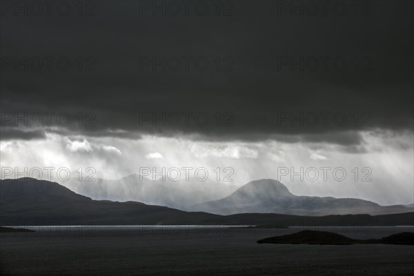 Black stormy sky and downpour during rain storm over desolate wilderness of Coigach