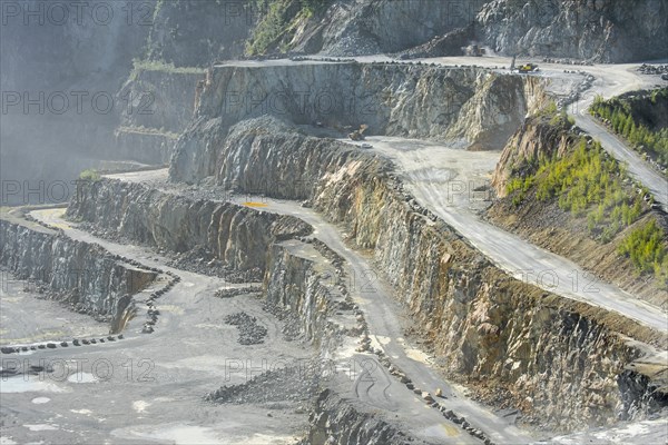 Heavy machines working in dusty porphyry quarry