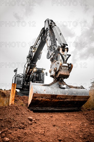 Black Liebherr crawler excavator excavating earth for house construction on building site