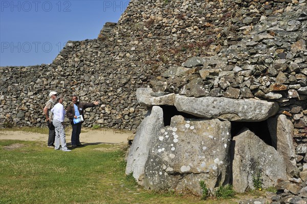Tourists with guide visiting entrance to one of the chambers of the Cairn of Barnenez