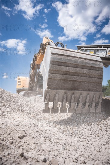 Yellow tracked excavator with large bucket for demolition recycling on construction site