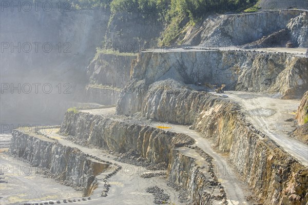 Heavy machines working in dusty porphyry quarry