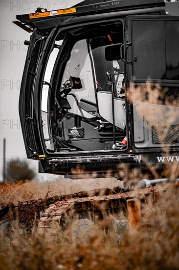 Black Liebherr crawler excavator excavating earth for house construction on building site