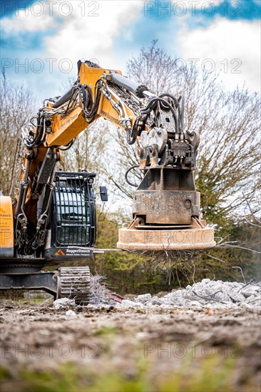 Yellow Liebherr crawler excavator with magnet recycling on demolition site