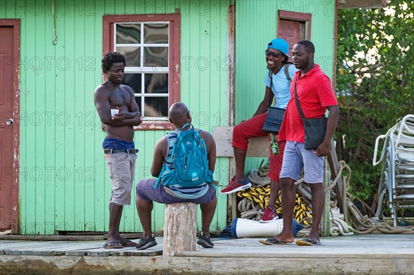 Local black men gathering at the colourful wooden docks in Marigot Bay on the island of Saint Lucia in the Caribbean Sea