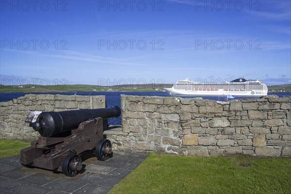 Cannon at 17th century Fort Charlotte in the centre of Lerwick and cruise ship in the Bressay Sound