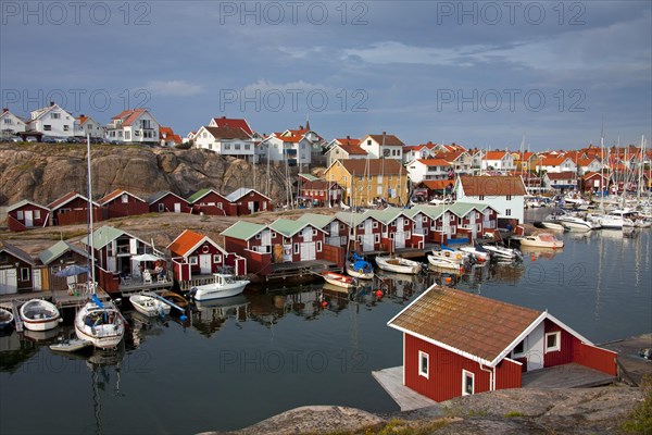 Colourful traditional fishing huts and boathouses along wooden pier at Smoegen