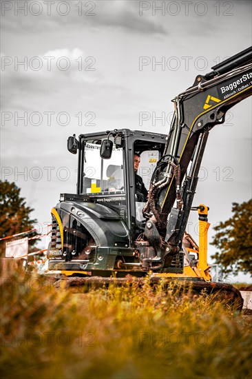 Black Yanmar tracked excavator during earthworks on house construction site