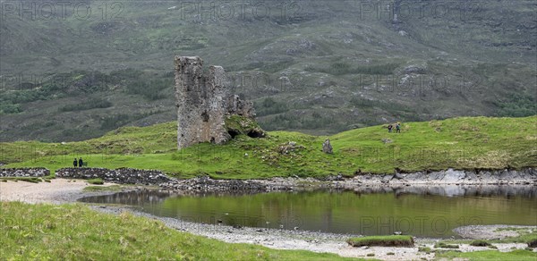 Tourists visiting 16th century Ardvreck Castle ruin at Loch Assynt in the Scottish Highlands