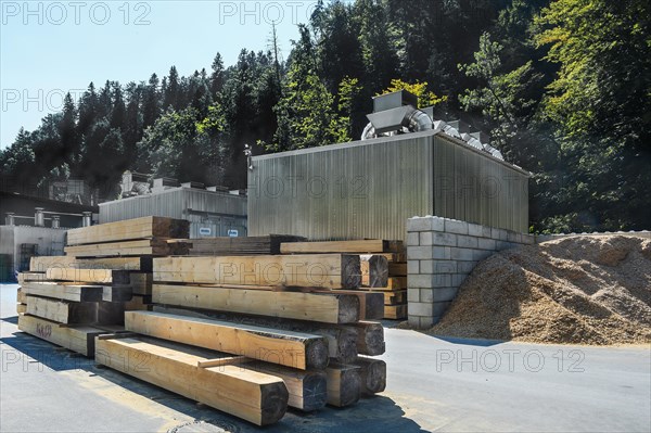 Wood beams and sawdust in front of a wood drying plant in a sawmill