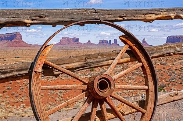 Buttes of Monument Valley seen through old wooden wagon wheel