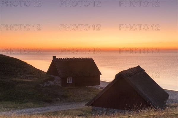 Two fishing huts at sunrise in summer along the Baltic Sea coast at Havaeng