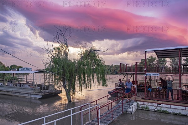 Western tourists and river taxis on the Orange river at sunset near Upington