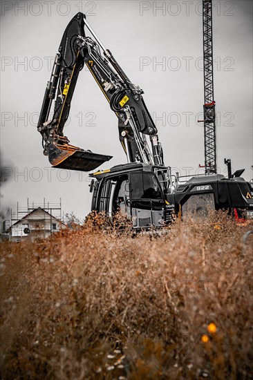 Black Liebherr crawler excavator excavating earth for house construction on building site