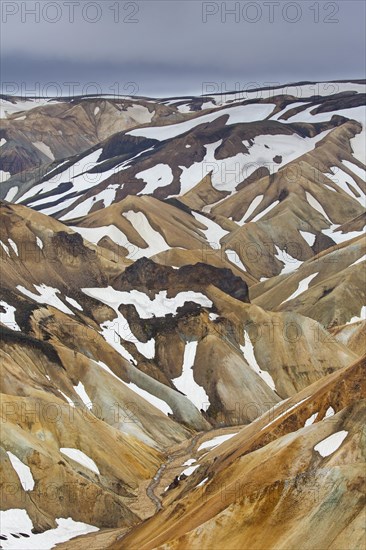 Sulphur coloured rhyolite mountains with patches of snow at Brennisteinsalda volcano near Landmannalaugar