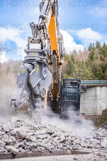 Yellow Liebherr crawler excavator with spreader recycling on demolition site