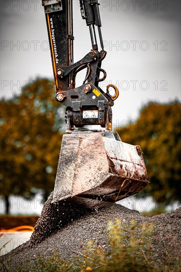 Excavator shovel unloads gravel on construction site