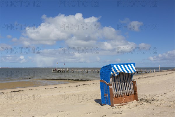 Roofed wicker beach chair and wooden jetty