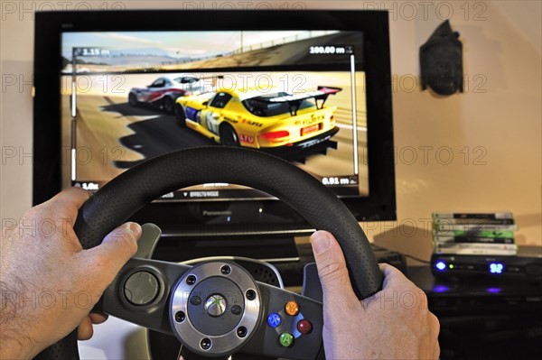 Steering wheel controller in front of television screen showing cars in racing game