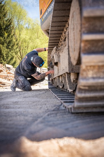 Man screwing on yellow Liebherr crawler excavator during recycling on demolition site