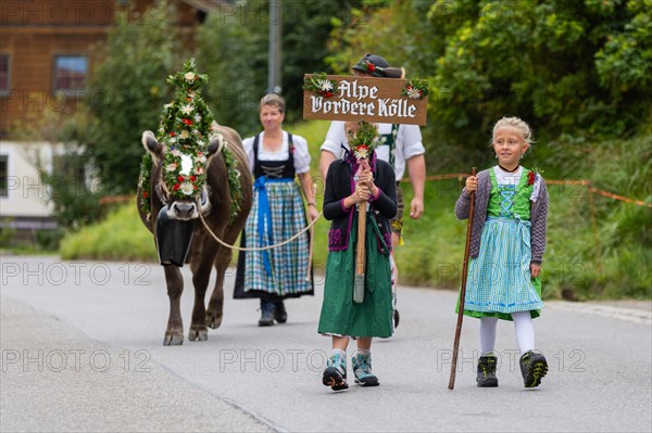 Girl in traditional traditional costume carrying alpine shield