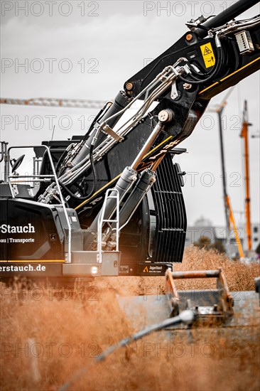 Black Liebherr crawler excavator excavating earth for house construction on building site