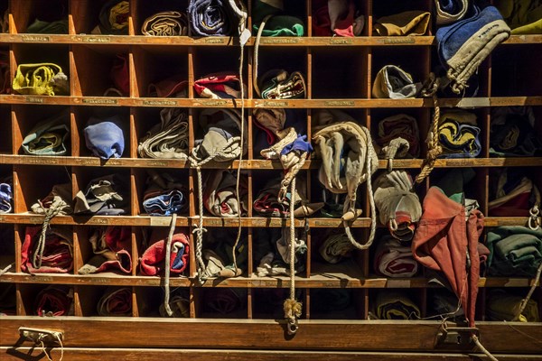 Variety of rolled up national flags in old wooden cupboard on board of ship