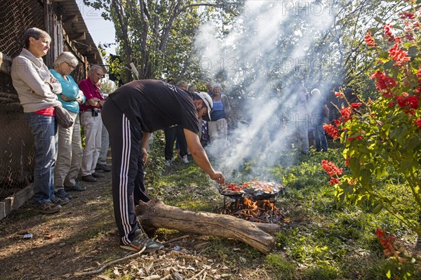 Kyrgyz man cooking food for tourists on a traditional stone barbecue in Kyrgyzstan