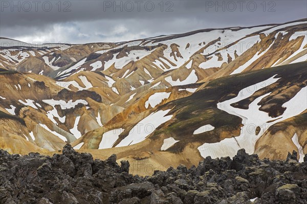 Lava field and sulphur coloured rhyolite mountains at Brennisteinsalda volcano near Landmannalaugar