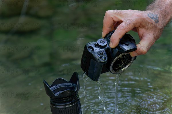 Man pulls his digital camera out of the river that has accidentally fallen into the river flooded from inside
