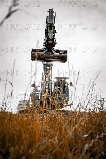 Black Liebherr crawler excavator excavating earth for house construction on building site