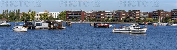 Illegally anchored houseboats in the Rummelsburg Bay with the residential houses on the Rummelsburg shore