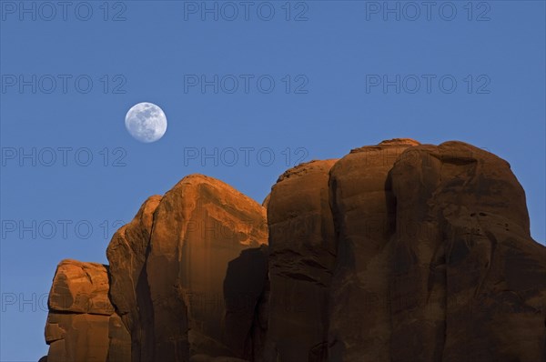 Red sandstone cliffs at sunset with full moon in the sky