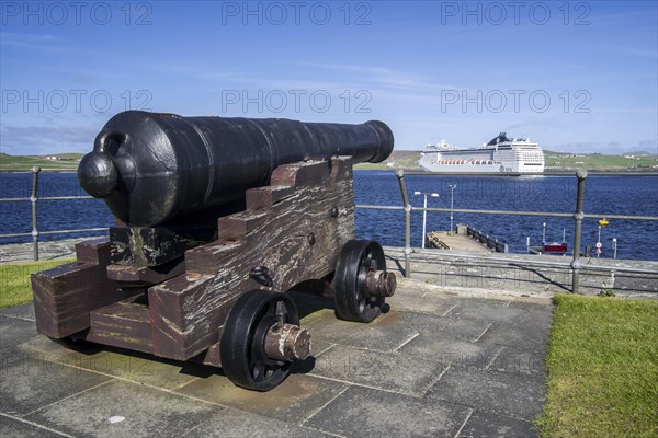 Cannon at 17th century Fort Charlotte in the centre of Lerwick and cruise ship in the Bressay Sound