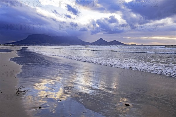 Rain clouds over the Table Mountain and sandy Sunset Beach on Woodbridge Island near Cape Town