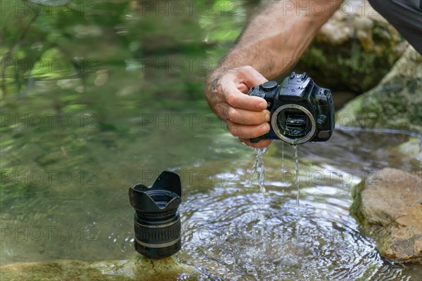 Man pulls his digital camera out of the river that has accidentally fallen into the river flooded from inside